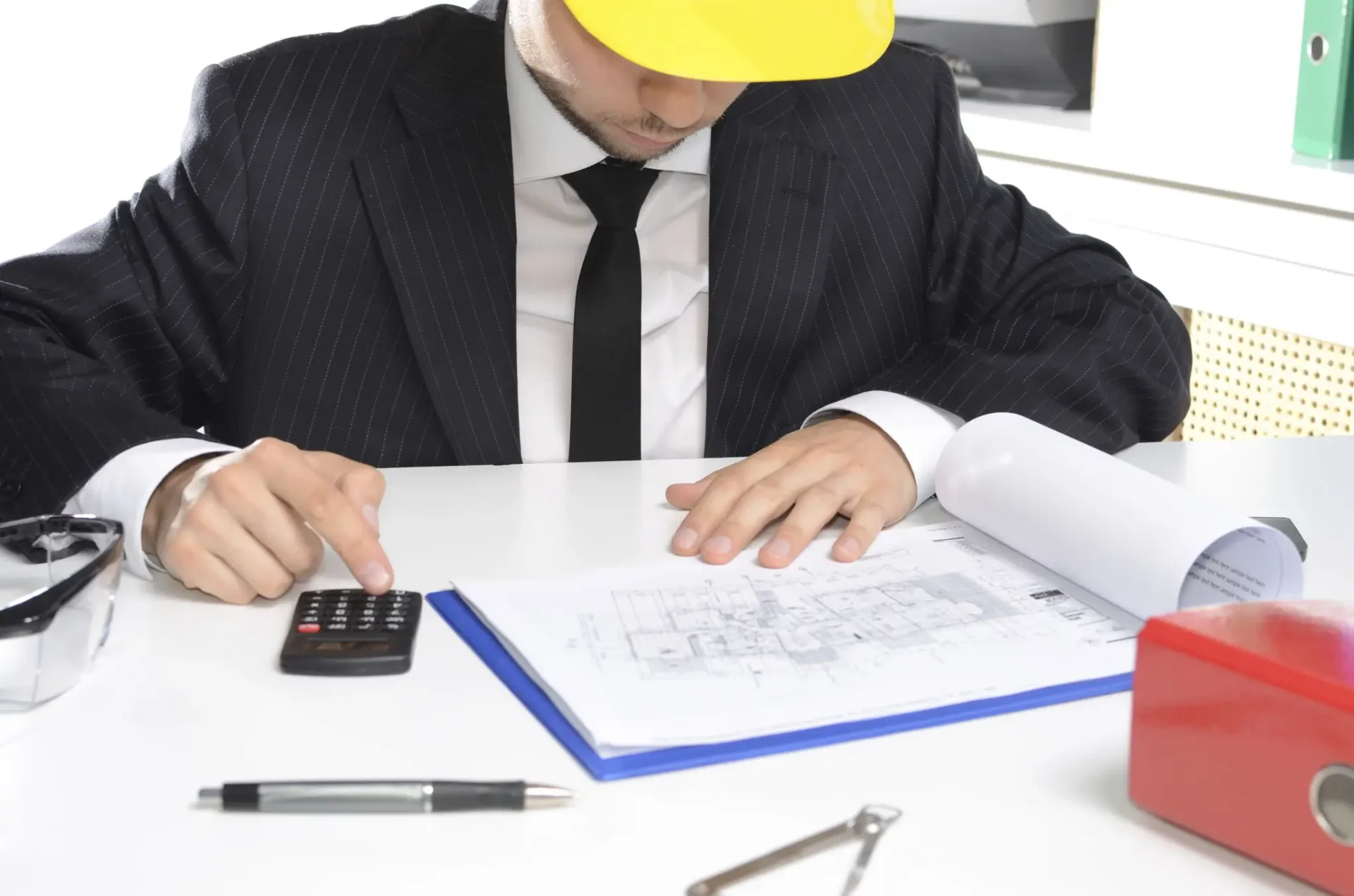 Engineer reviewing blueprints with a calculator.