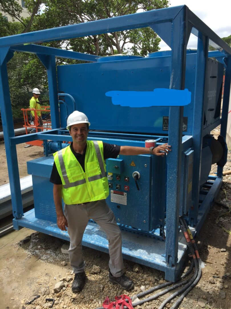 Worker standing by blue industrial machine.