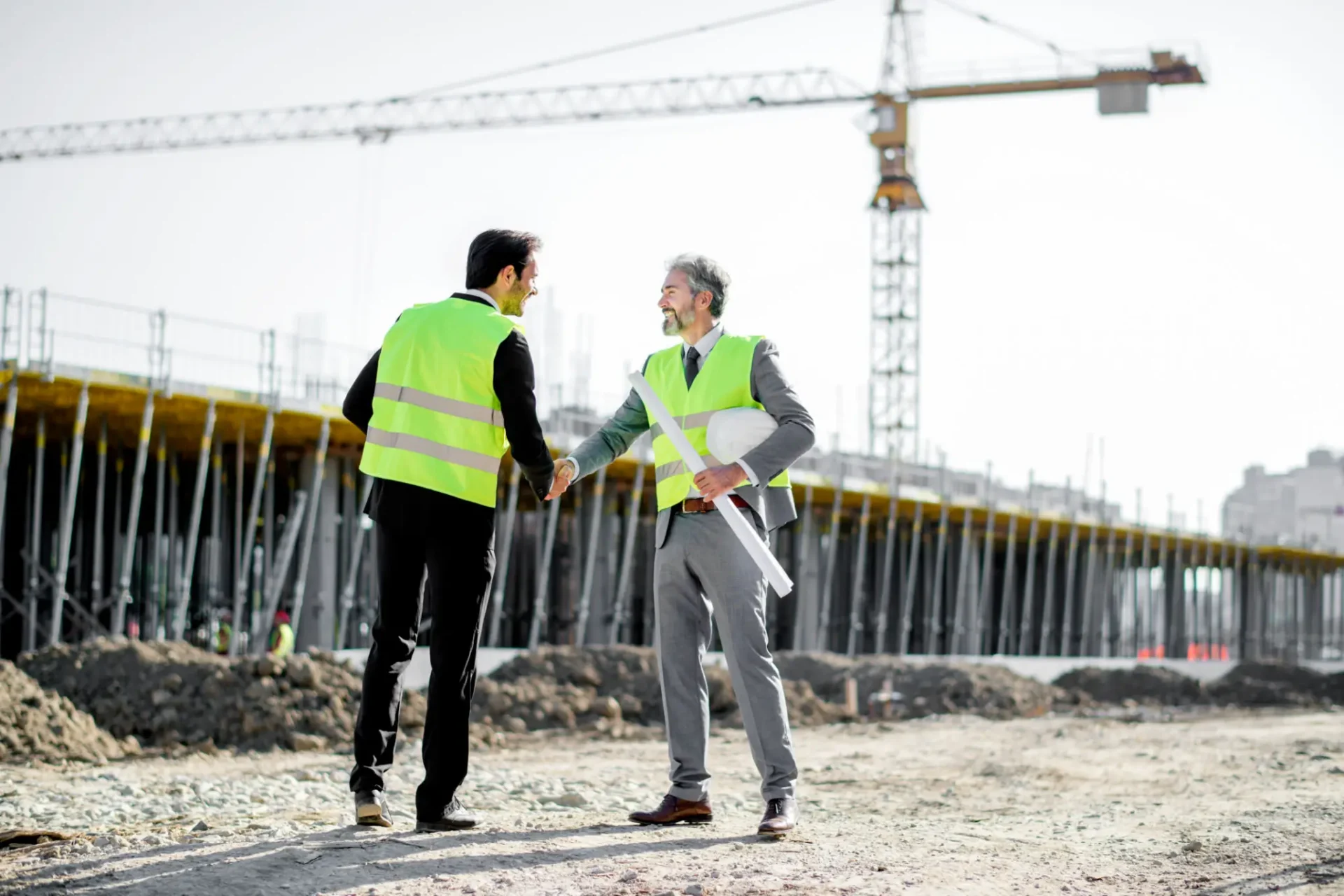 Two men shaking hands at construction site.