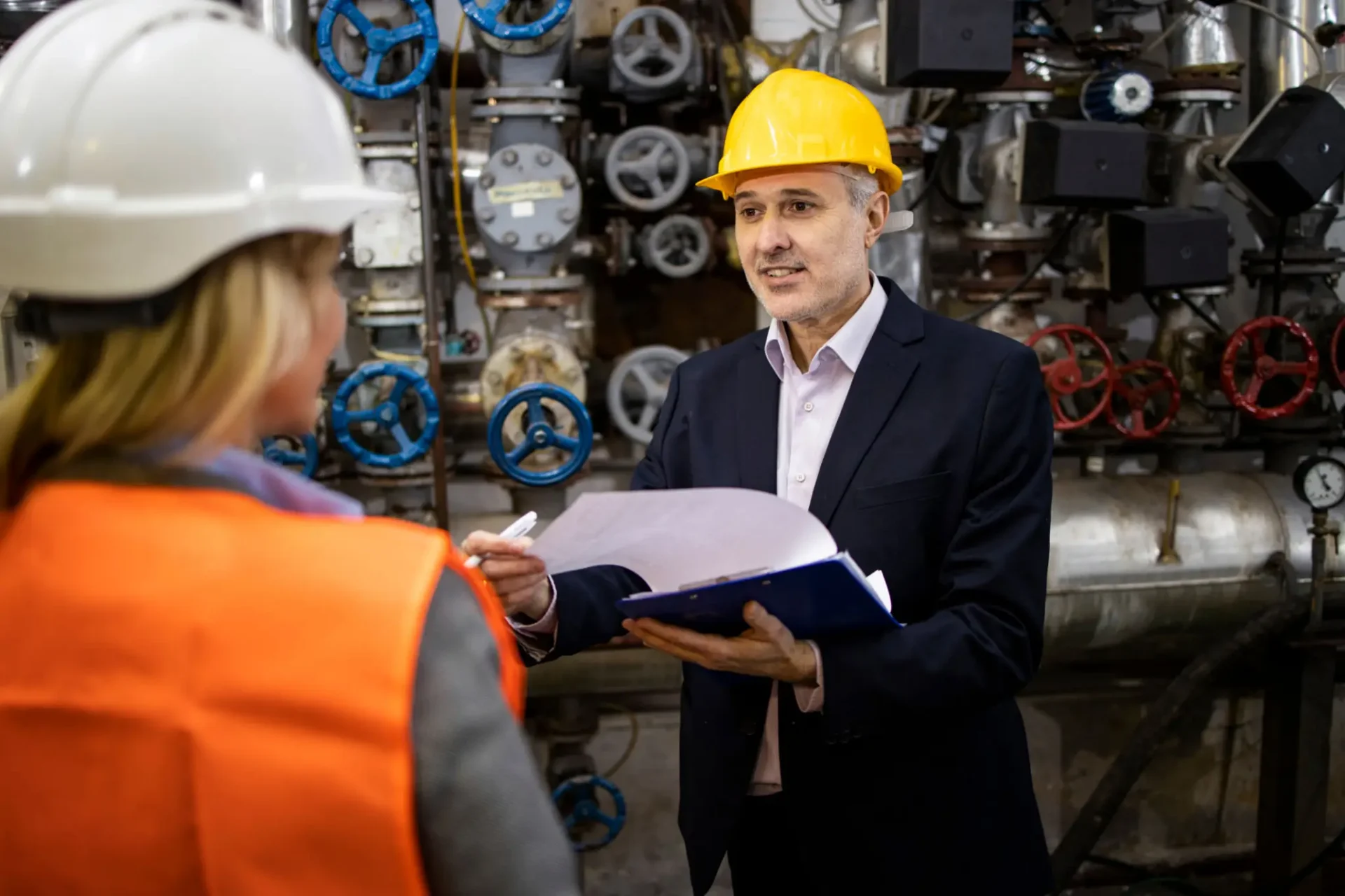 Industrial workers discussing in machinery room.