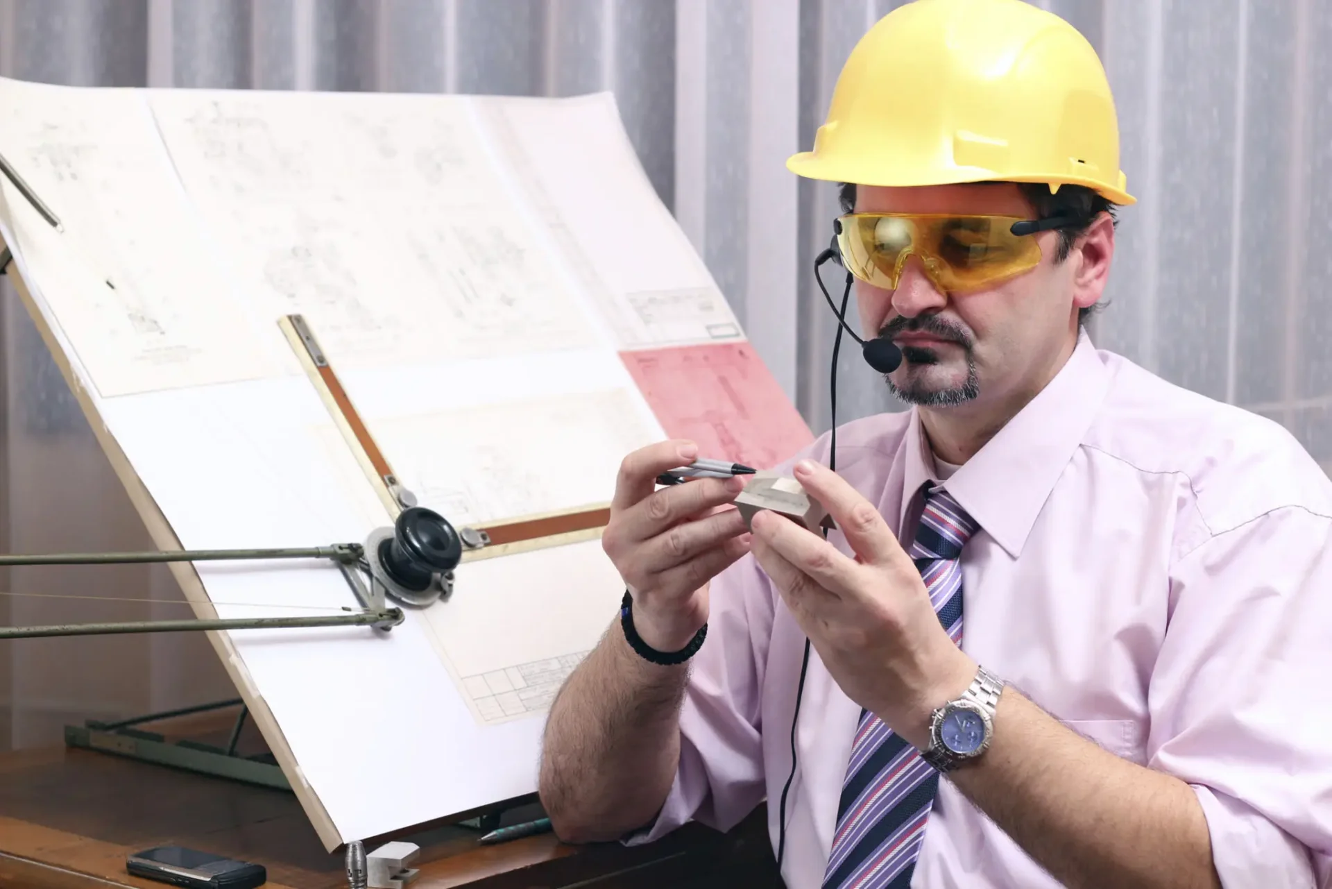 Engineer examining object at drafting table.