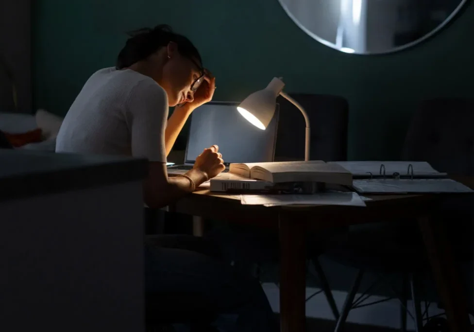 Person studying late under desk lamp